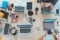 The image shows the top view of a large conference table with laptops.