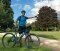 The image shows a man with a bicycle in front of a landscape.